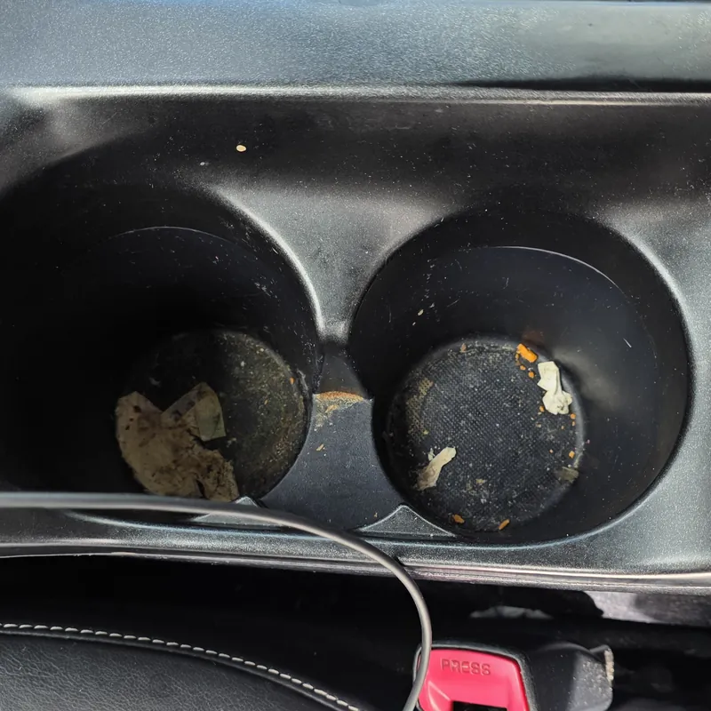Cup holders filled with grime and debris before an interior deep clean in Wembley