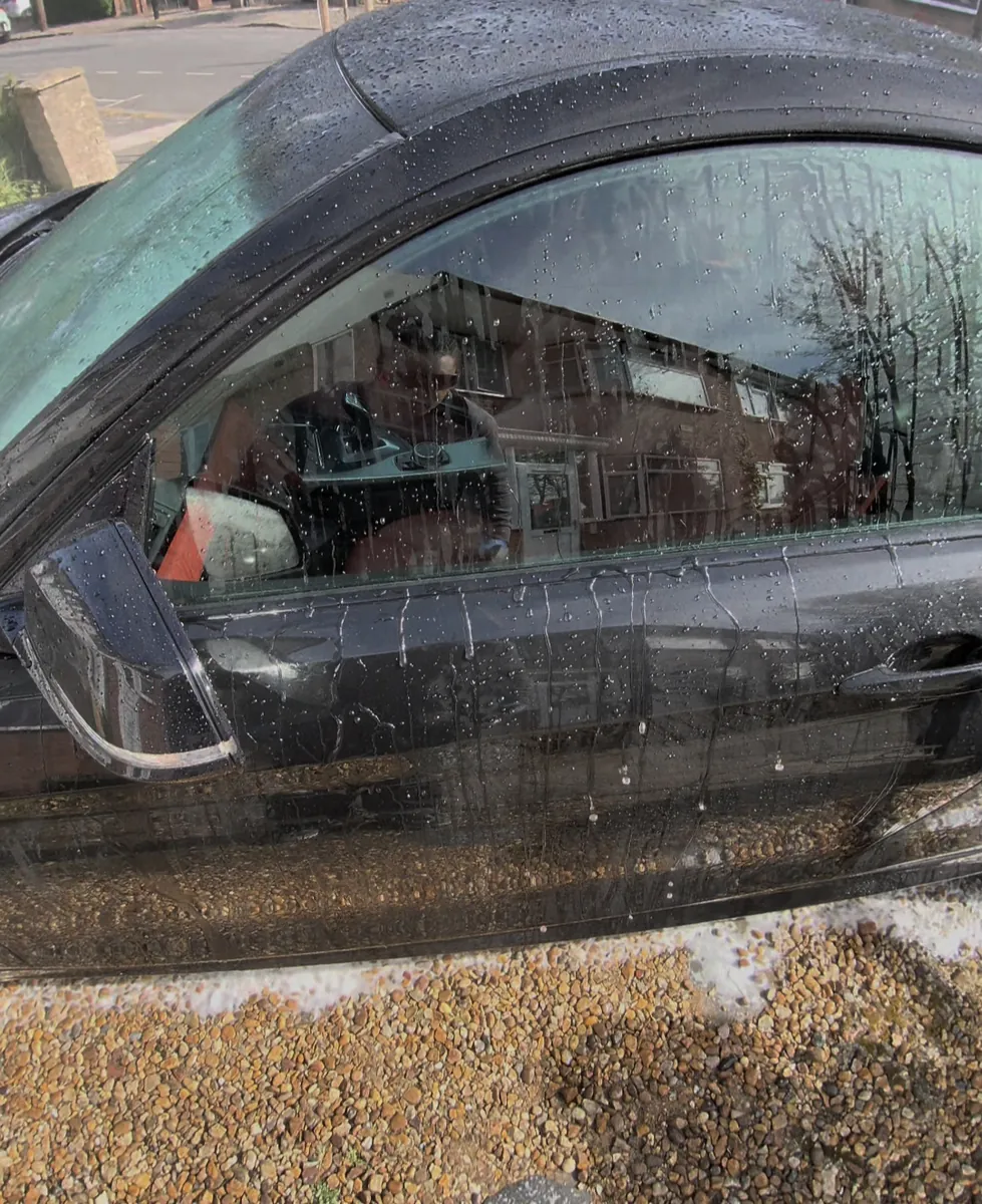 Water sheeting off a black convertible during a mobile detail